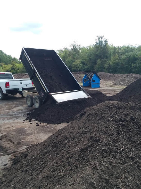 dump trailer dumping topsoil on the screening and sales pad